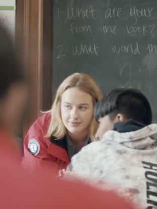 blonde girl in a classroom in front of a chalkboard