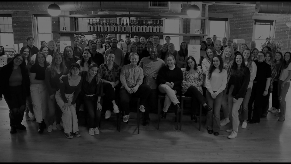 black and white image of a large group of people smiling at a bar