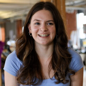 woman with brown hair and a blue shirt sitting in an office