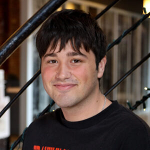 guy with red and black shirt sitting on spiral staircase in front of a fish tank