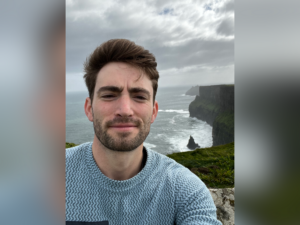 Man standing in front of the Irish Cliffs of Moher on a cloudy day