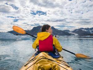 woman in a canoe on a lake with clouds above