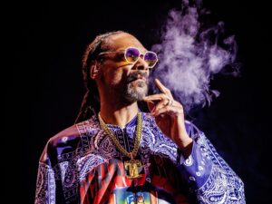 Snoop Dogg smoking against a dark background