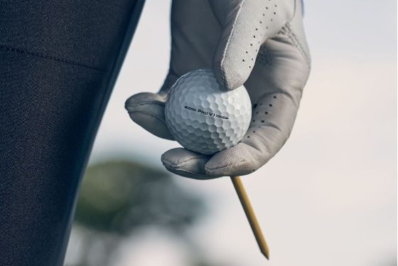 Close up of a golfer holding a ball on a tee