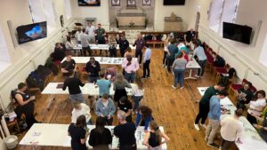 Aerial photo of groups of people standing around tables playing a game