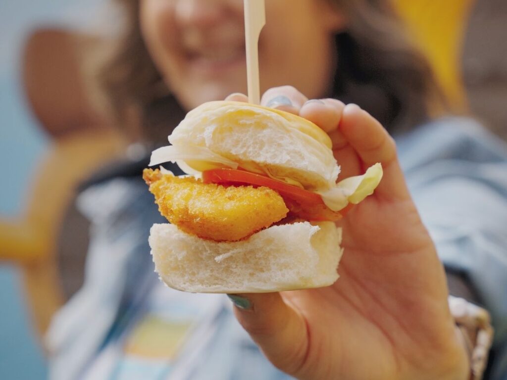 Hand holding fried fish sandwich