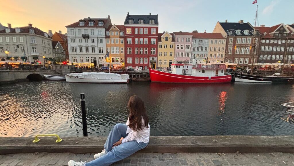 woman sitting by colorful, riverside European homes