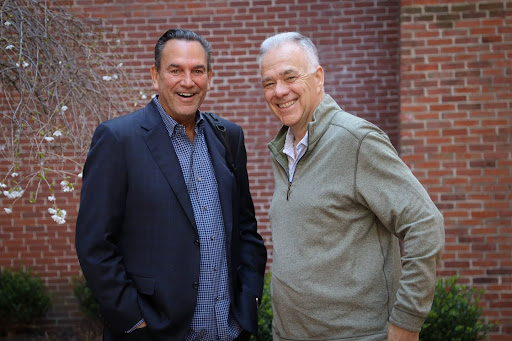 two men in front of a brick wall